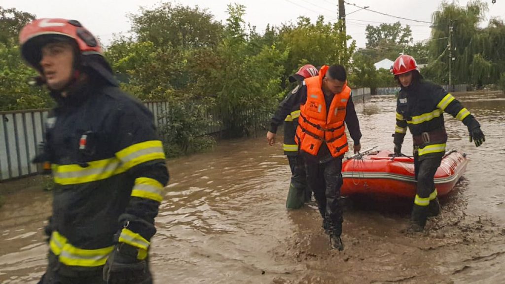 Rescuers drag a boat on a flooded street in Pechea, Romania, Saturday, Sept. 14, 2024 after torrential rainstorms left scores of people stranded in flooded areas.