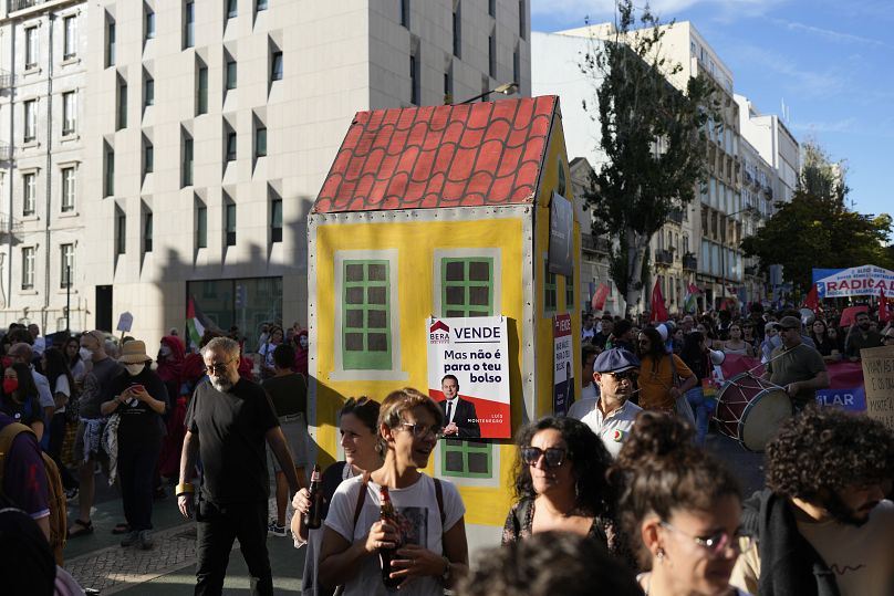 Des militants poussent un faux bâtiment avec des affiches de style immobilier présentant des photos du Premier ministre Luís Monténégro lors d'une manifestation à Lisbonne, le 28 septembre 2024.