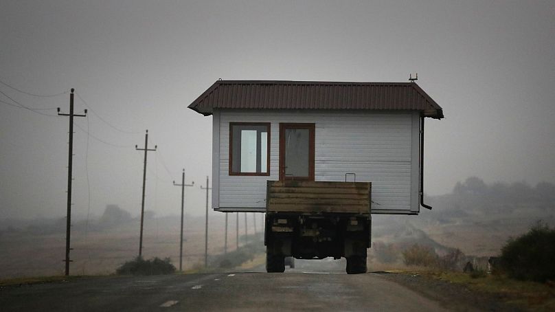 Une famille arménienne conduit un camion chargé d'une petite maison le long d'une autoroute alors qu'elle quitte son village natal du Haut-Karabakh, le 18 novembre 2020.