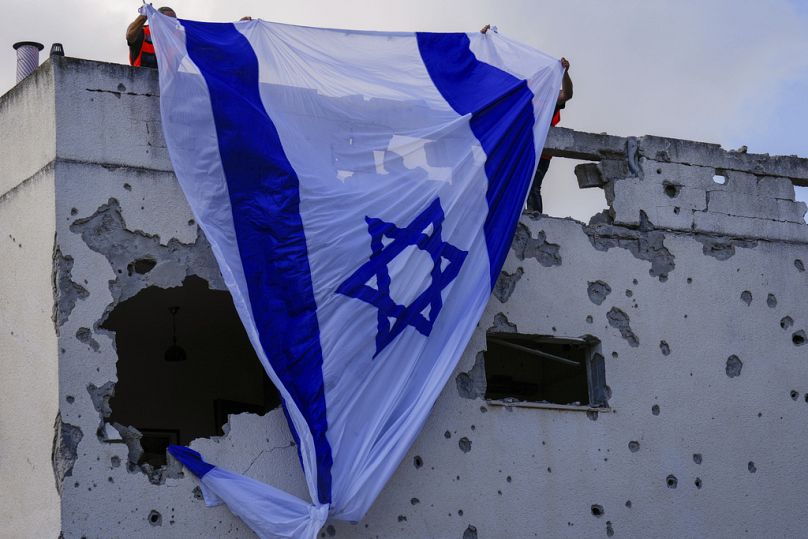 Des employés municipaux accrochent un drapeau israélien sur un bâtiment endommagé qui a été touché par une roquette tirée depuis le Liban, à Kiryat Bialik, dans le nord d'Israël, le dimanche 22 septembre 2024.