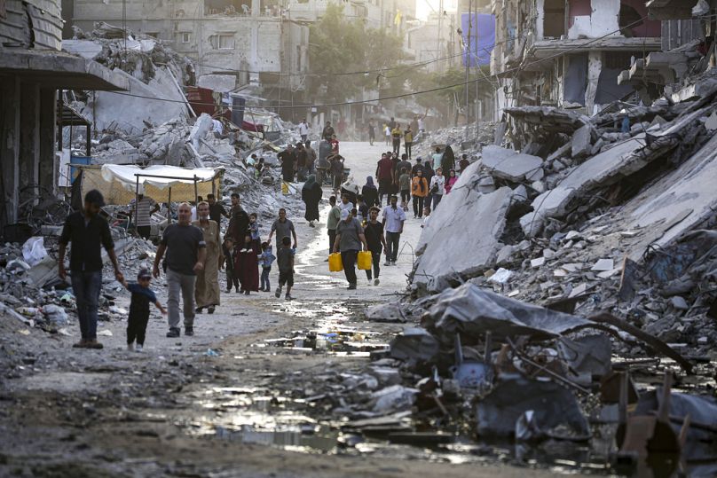 Des Palestiniens déplacés par l'offensive israélienne sur la bande de Gaza traversent une traînée sombre d'eaux usées qui se déversent dans les rues de la ville de Khan Younis, dans le sud du pays, en juillet 2024.