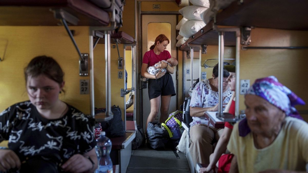 A girl calms her sister on an evacuation train in Pokrovsk, Donetsk region, Ukraine, Friday, Aug. 23, 2024.