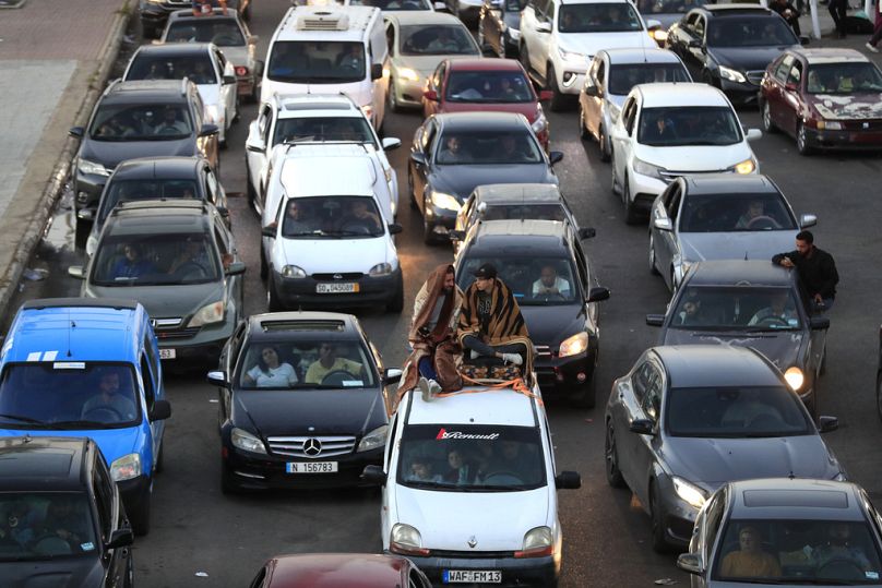 Des citoyens libanais qui ont fui les villages du sud au milieu des frappes aériennes israéliennes en cours lundi, sont assis sur leurs voitures sur une autoroute qui relie la ville de Beyrouth, dans la ville portuaire du sud de