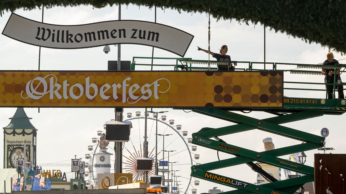 Workers stand on a lifting platform during construction work on the Oktoberfest grounds at the festival