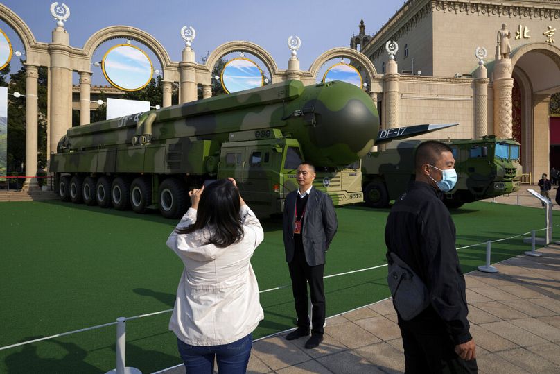 Des visiteurs visitent des véhicules militaires chinois transportant des missiles balistiques Dong Feng 41 et DF-17 lors d'une exposition à Pékin.