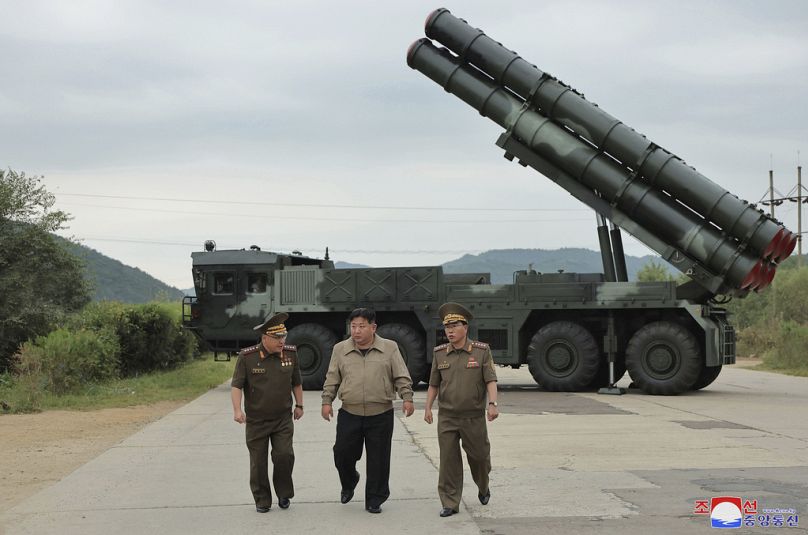 Kim Jong Un, au centre, marche avec d'autres responsables près de ce qui semble être leur nouveau véhicule de lancement de roquettes multiples de 600 mm dans un lieu non divulgué en Corée du Nord.