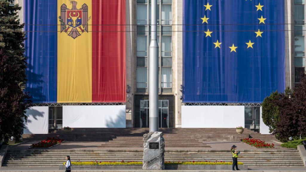 FILE - A woman runs past the government building, decorated with European Union and Moldovan flags in Chisinau, Moldova, on May 31, 2023