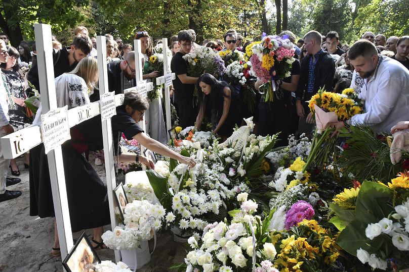 Des gens déposent des fleurs sur les tombes des membres de la famille de Yaroslav Bazylevych dans un cimetière de la ville de Lviv, le 6 septembre 2024.