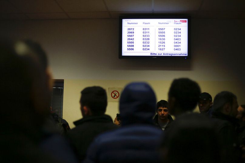 Des réfugiés attendent devant un écran d'information avant de se rendre chez un administrateur du centre d'accueil central pour demandeurs d'asile à Berlin, en Allemagne, le mardi 3 mars 2015.