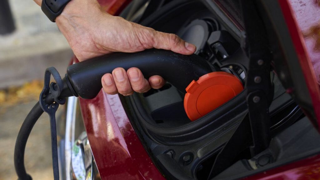 A man charges his electric car at an electrical charging point.