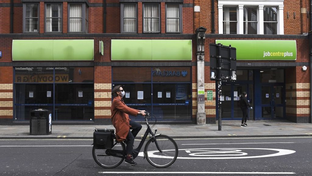 A woman cycles past a job centre in London