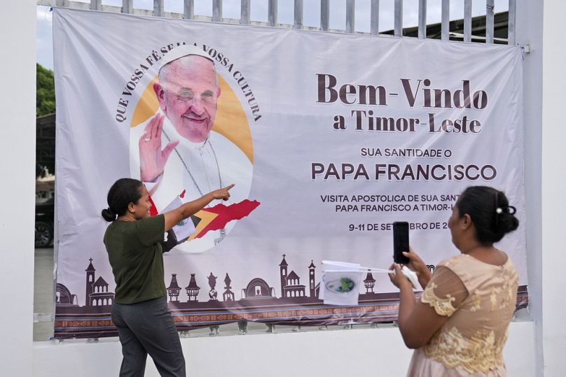 Une femme se fait prendre en photo avec une banderole accueillant le pape François avant sa visite au Timor oriental, à Dili, le dimanche 8 septembre 2024. 