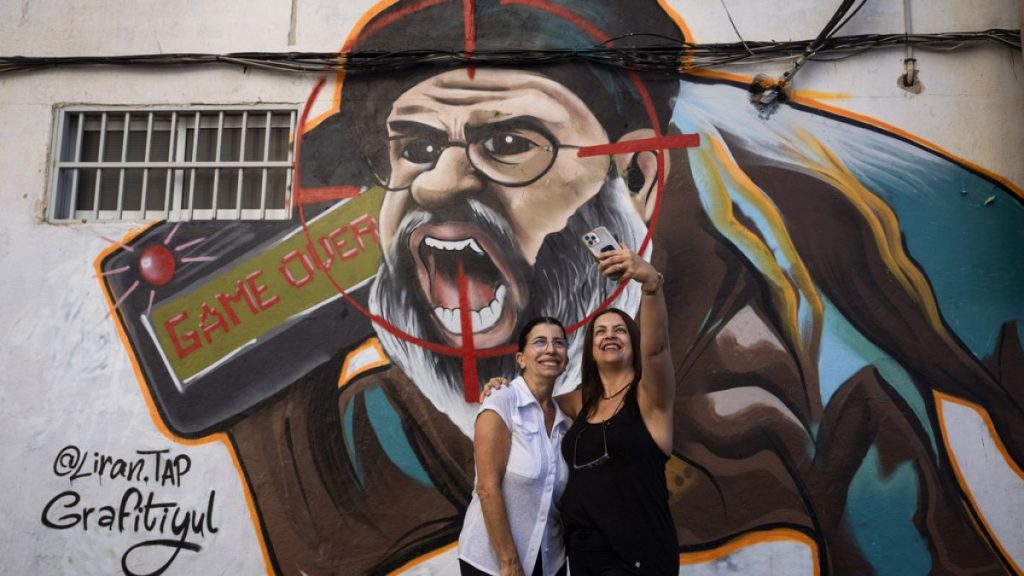 Two women take a selfie next to a newly painted graffiti of Hezbollah leader Hassan Nasrallah, Tel Aviv, Israel, September 29th 2024