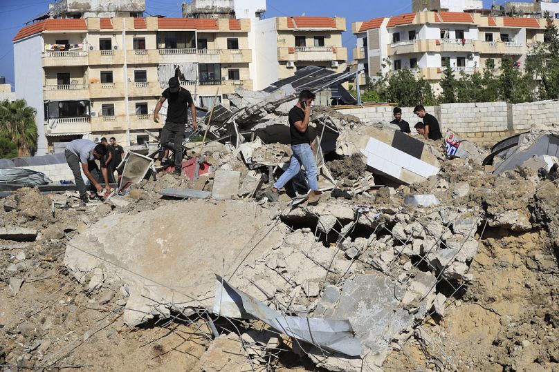 Des gens se rassemblent sur le site d'une frappe aérienne israélienne qui a touché un hangar dans la ville de Jiyeh, dans le sud du Liban, le mercredi 25 septembre 2024.