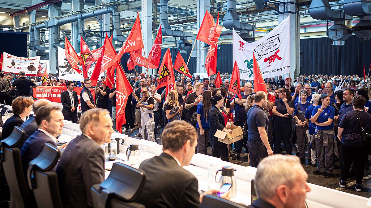 Employees protest before the start of a works meeting in a hall at the VW plant in Wolfsburg