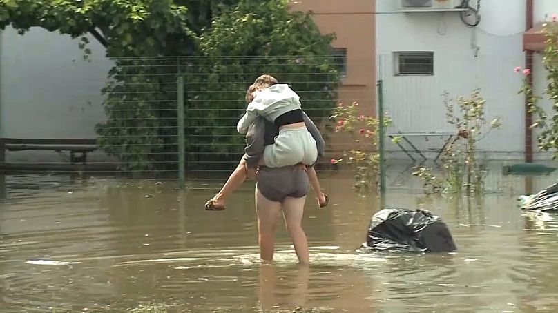 Une femme porte un enfant dans les eaux de crue à Constanta, le 31 août 2024