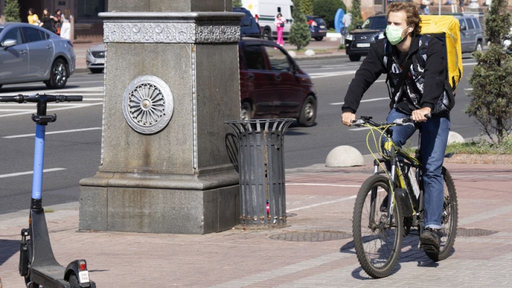 A delivery cyclist wearing a face mask cycles down a street in Kyiv, Ukraine, Friday Sept. 20, 2024