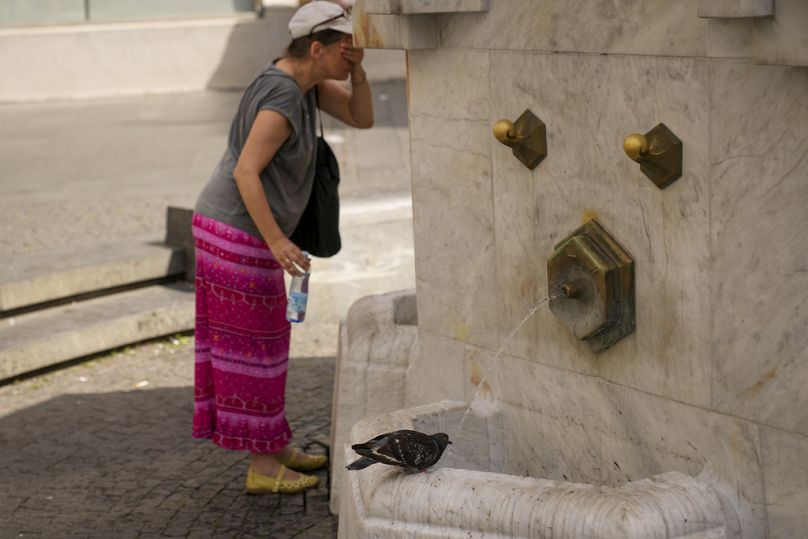 Une femme se rafraîchit pendant qu'un pigeon boit de l'eau d'une fontaine publique à Belgrade, en Serbie.