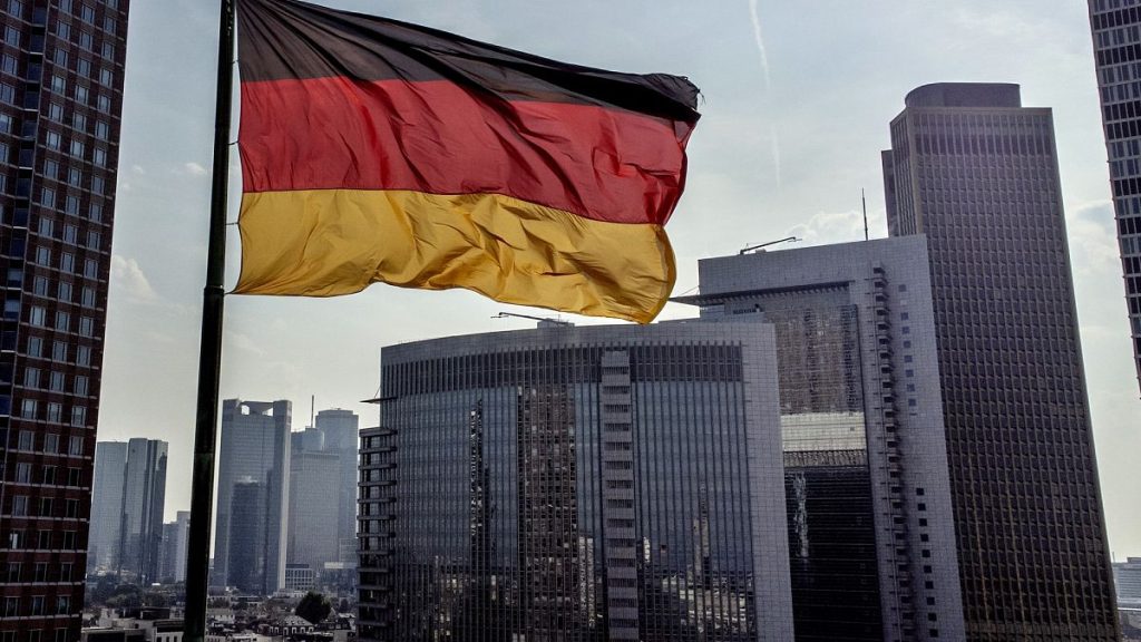 A German flag waves in front of the buildings of the banking district in Frankfurt, Germany