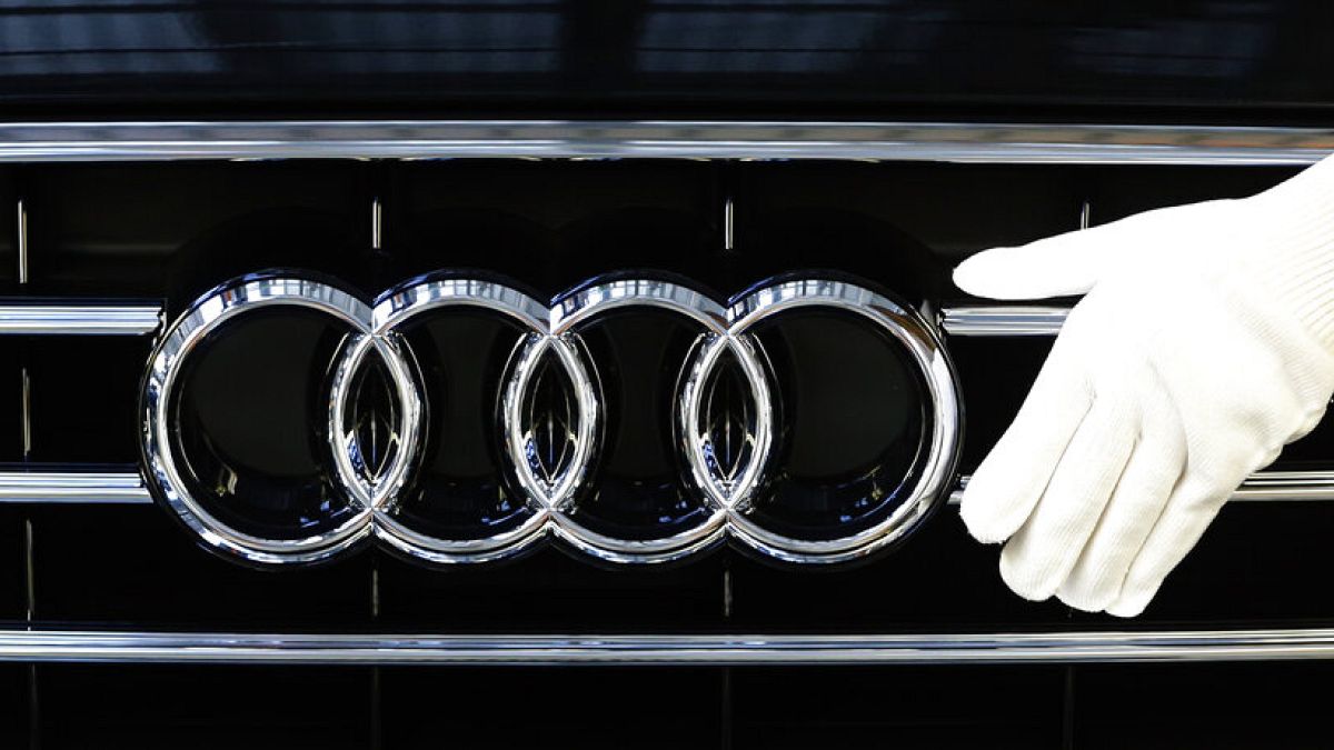 An employee of German car producer Audi fixes a car bonnet emblem as he assembles Audi A 8 models at their production site in Neckarsulm, Germany, Thursday, May 21, 2015.