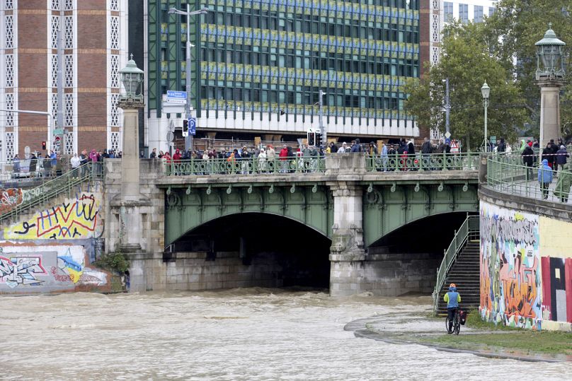 Les gens regardent la jonction de la rivière Vienne et du canal du Danube alors qu'ils inondent leurs rives dans le centre de Vienne, en Autriche, le dimanche 15 septembre 2024.