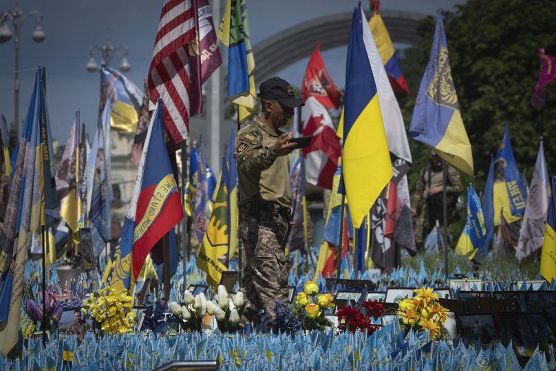 Un soldat volontaire colombien de la Légion internationale d'Ukraine réalise une vidéo sur un mémorial improvisé pour les soldats ukrainiens tombés au combat sur la place de l'Indépendance à Kiev, en juillet 2023