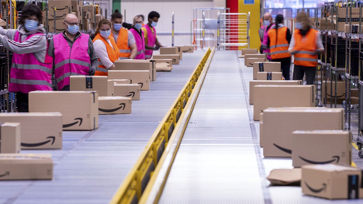 Employees sort parcels on a conveyor belt at a distribution center of an online retailer.