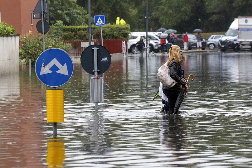 Deux femmes pataugent dans les eaux de crue causées par de fortes pluies dans une rue de Milan, le 5 septembre 2024