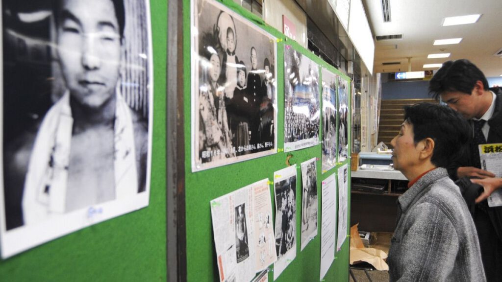 Hideko Hakamada, sister of death row inmate Iwao Hakamada, seen at left on the wall, looks at their family photos at a Tokyo gym, Thursday, Jan. 24, 2008