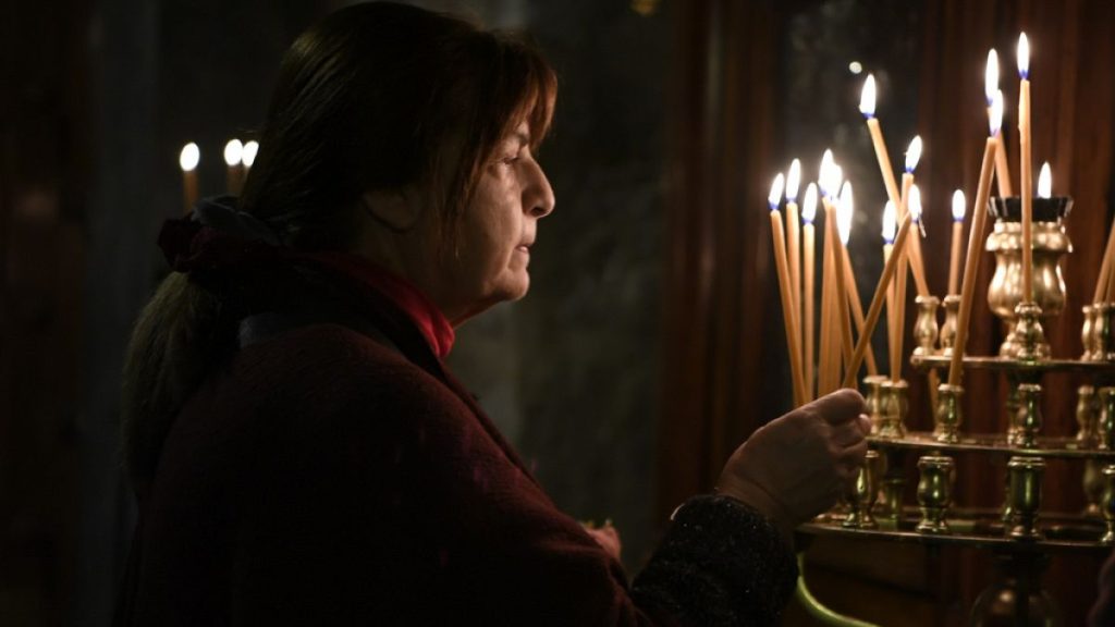 A woman lights a candle during a Christmas Divine Liturgy, in the Greek Orthodox Church of Panagia (Virgin Mary) Kapnikarea in Athens, 25/12/2023