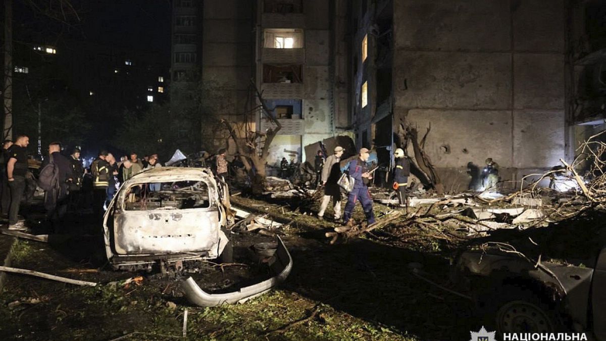 People mill around damaged cars and debris after a Russian strike on a residential building in Kharkiv, Ukraine early Sunday Sept. 22, 2024.