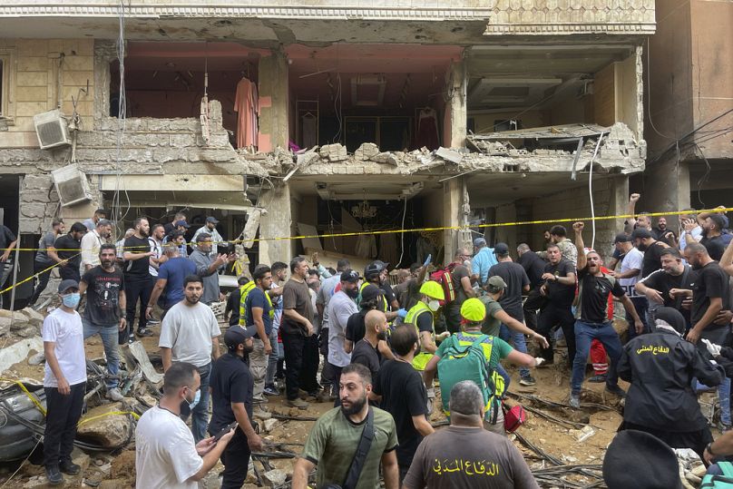 Des gens se rassemblent près d'un bâtiment endommagé sur le lieu d'une frappe de missile israélien dans la banlieue sud de Beyrouth.