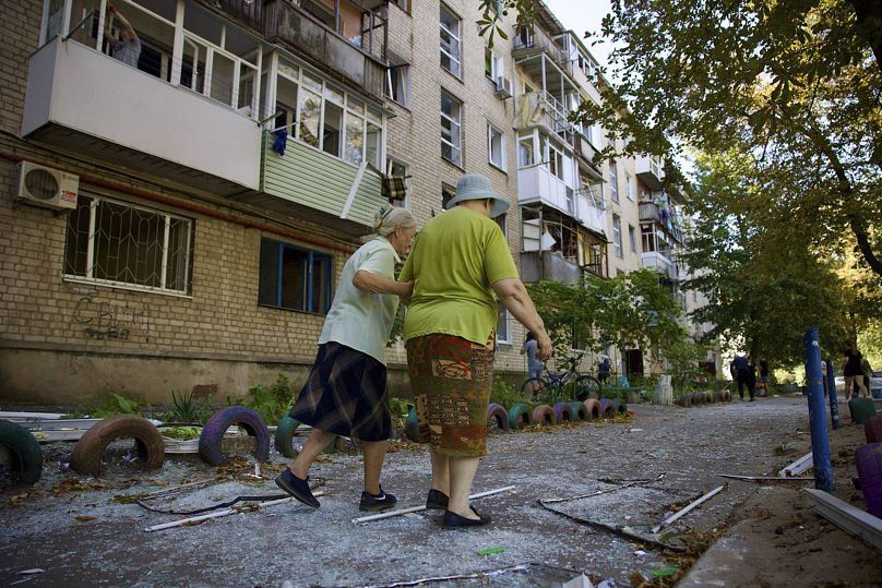 Des femmes locales marchent près d'un immeuble résidentiel endommagé par une frappe russe à Pavlohrad, le 6 septembre 2024