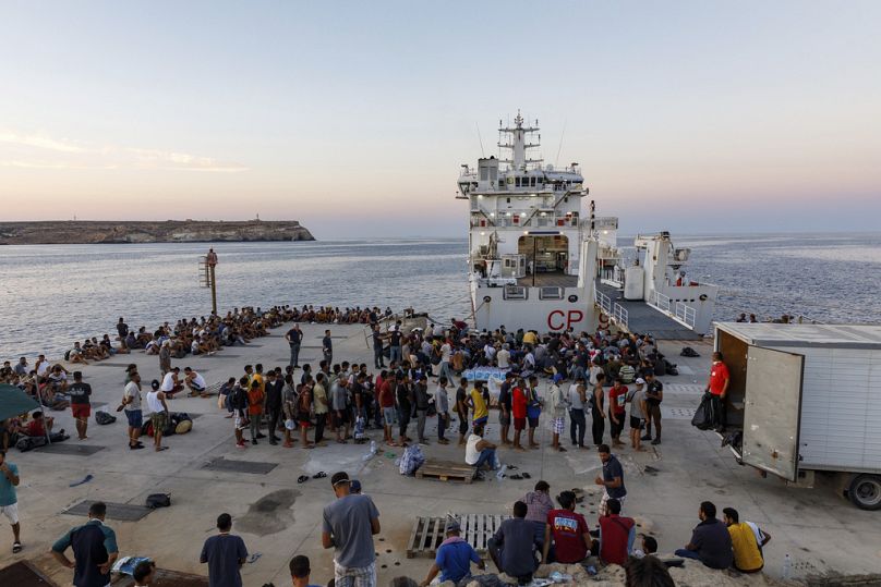 FILE - Migrants wait to board an Italian Coast Guard ship in the Sicilian Island of Lampedusa, Italy, Wednesday, 3 August, 2022. 