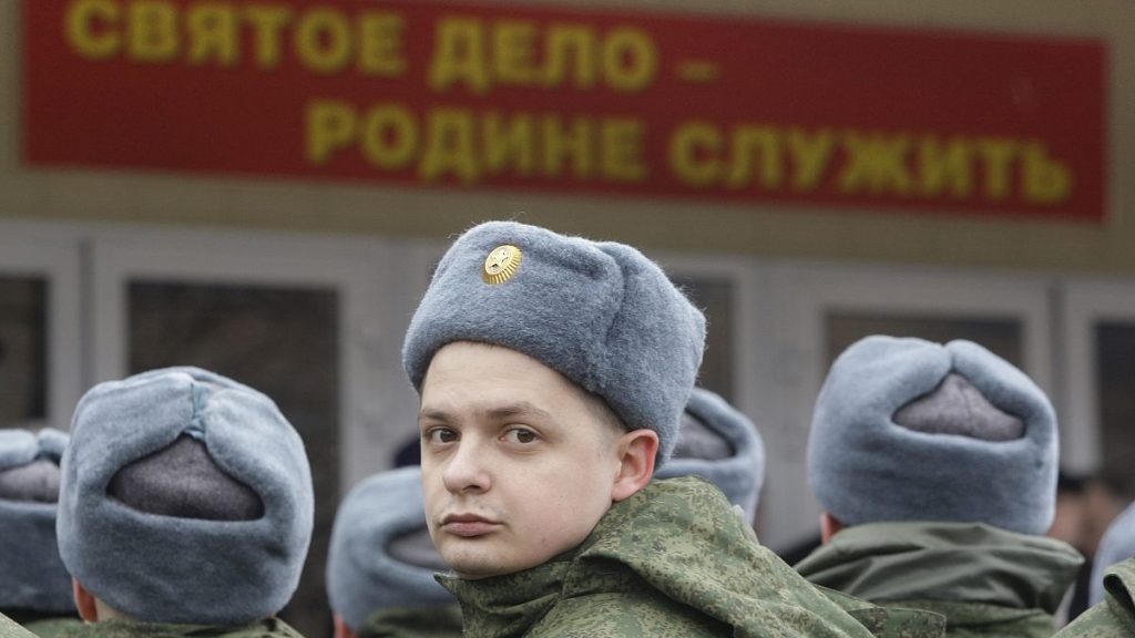 Russian military conscripts line up under a sign saying