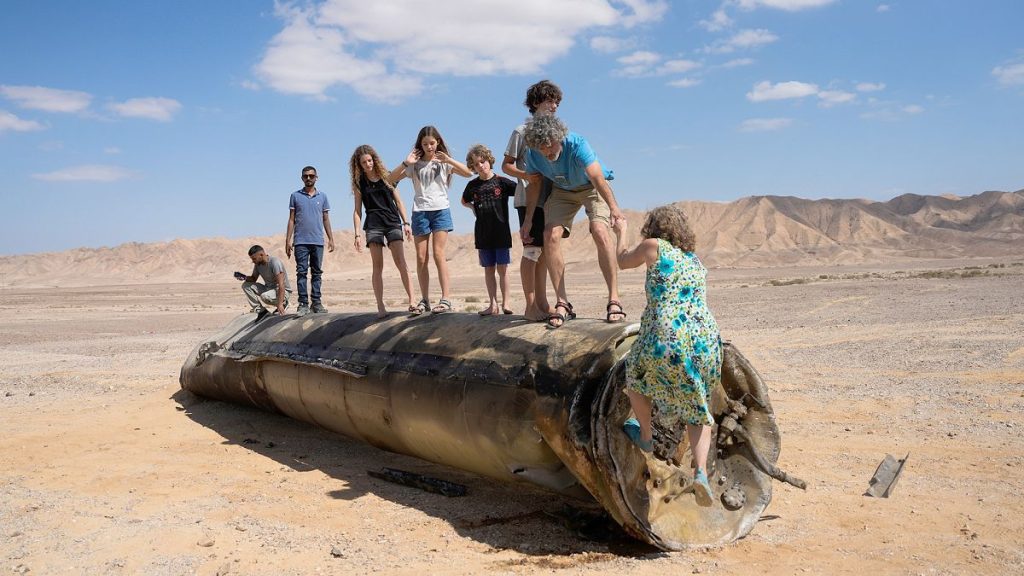 People climb on the debris of an Iranian missile intercepted by Israel, near Arad, 2 October 2024