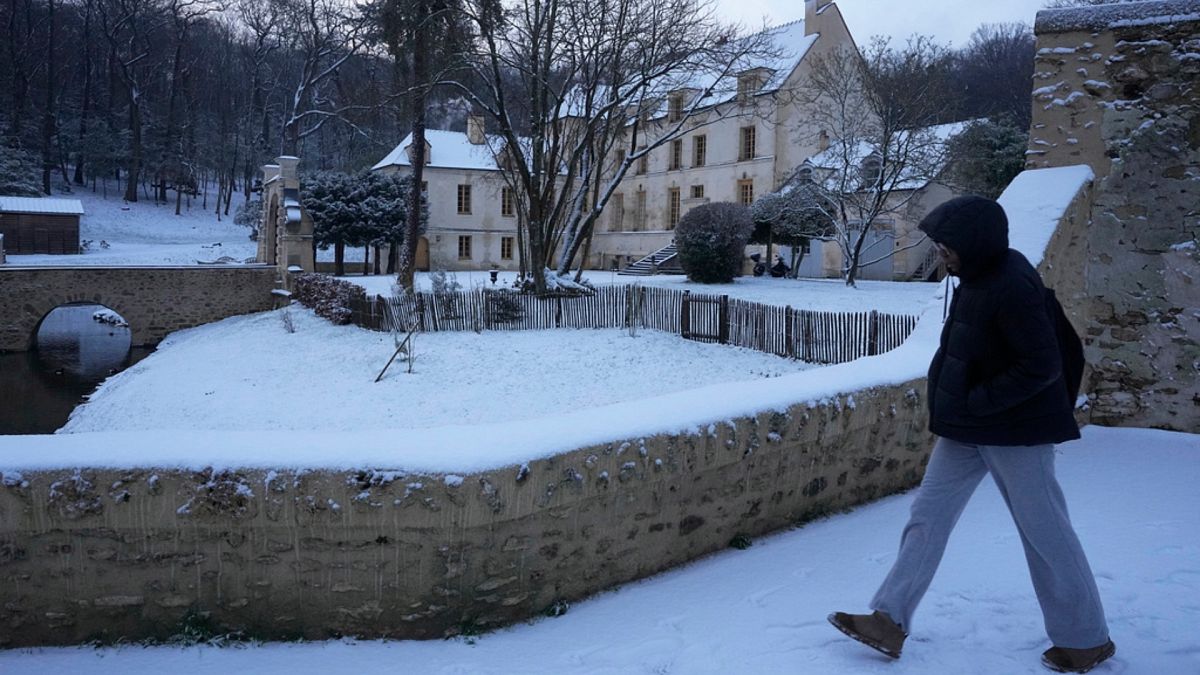 A person walks in the snow by the Chateau du Pont in Louveciennes, west of Paris.