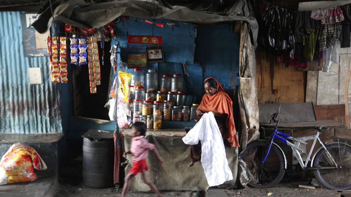 File photo. Indian woman Amina Shah, a microfinance beneficiary, stitches a shirt as she waits for customers at her shop in a slum in Mumbai, India. 7 March 2011.