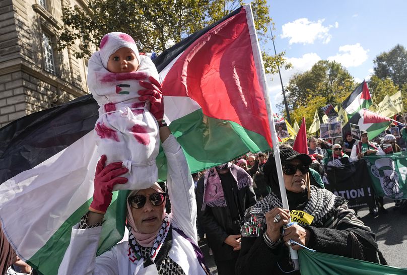 Un manifestant tient une poupée peinte avec du faux sang lors d'un rassemblement de soutien à la Palestine et au Liban à Paris, le 5 octobre 2024.