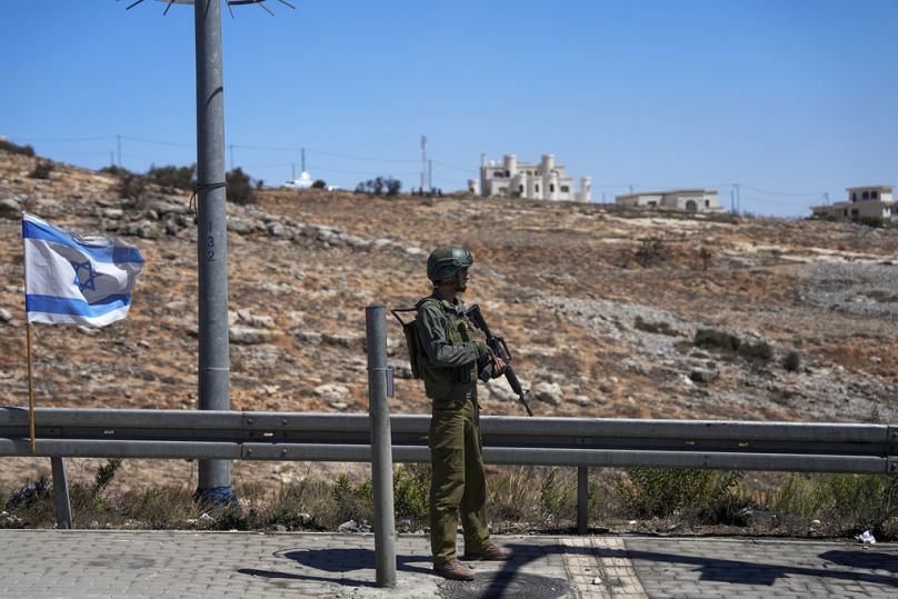 Un soldat israélien monte la garde à côté de la scène de ce qu'ils disent être une attaque à la bélier palestinienne dans une gare routière près de l'implantation juive de Beit El en Cisjordanie, mercredi.