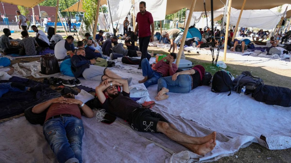 Migrants seek shelter outside an overcrowded asylum seekers center in Ter Apel, northern Netherlands, Thursday, Aug. 25, 2022.