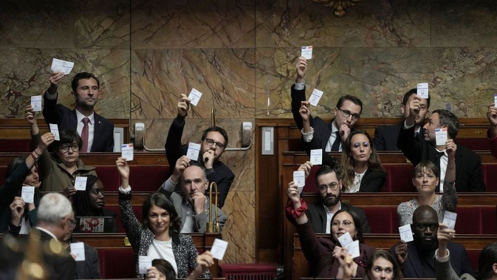 Members of the French unbowed party show their voting cards during the speech Prime Minister Michel Barnier arrives at the National Assembly, in Paris on 1 October.