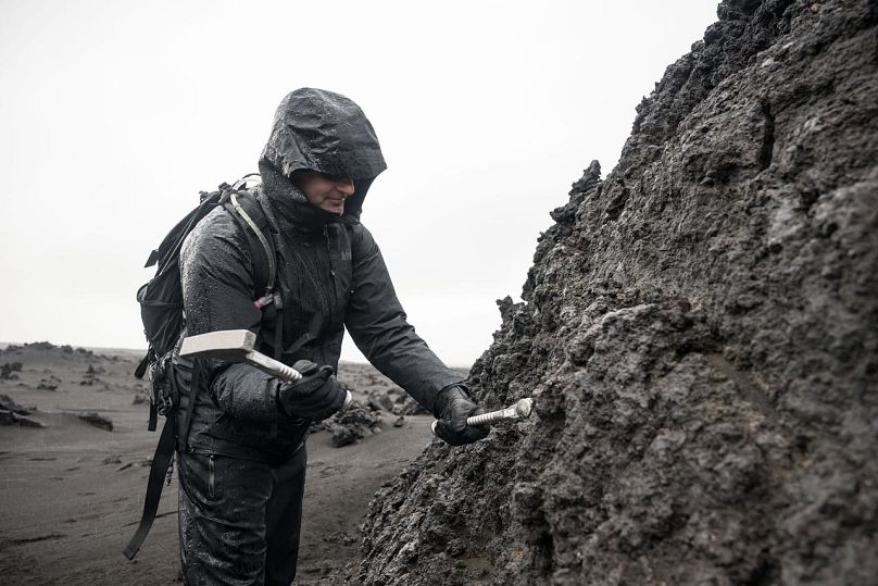 L'astronaute de l'ASC (Agence spatiale canadienne) et membre de l'équipage d'Artemis II Jeremy Hansen utilise un marteau-piqueur pour briser un échantillon de roche lors d'un exercice d'entraînement en Islande. 