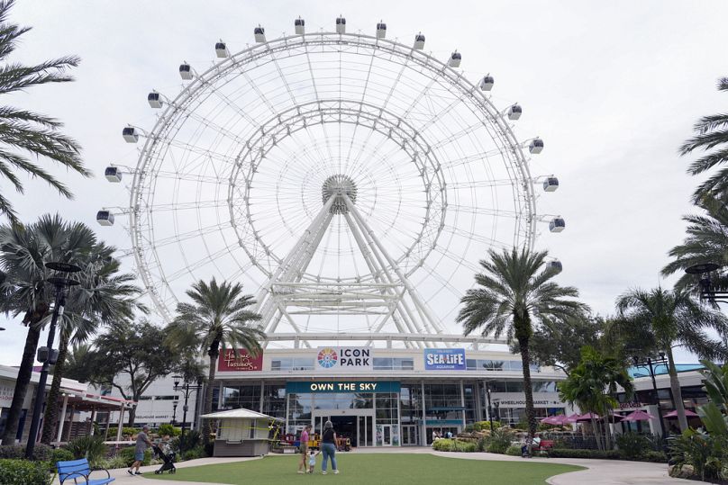 Les touristes d'Icon Park se promènent près de la grande roue Orlando Eye qui a été fermée alors que l'ouragan Milton menaçait la Floride mardi