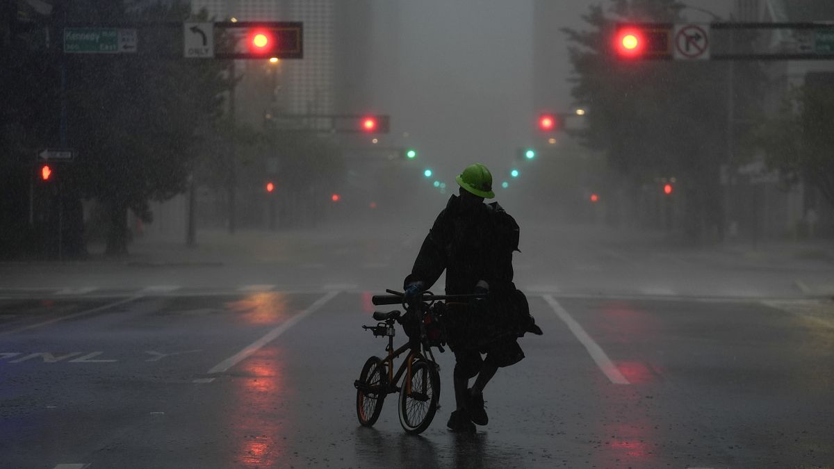 A man walks through windy and rainy conditions on a deserted street in downtown Tampa.