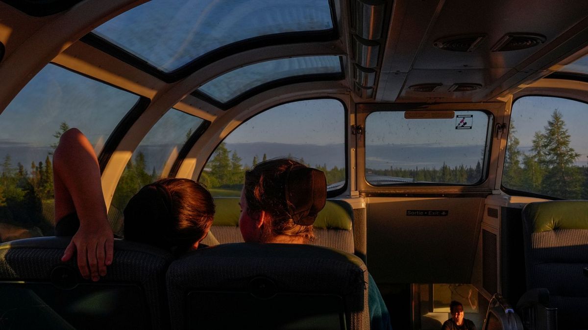 Passengers relax inside the skyline car as the sun sets Thursday, Aug. 8, 2024, between Churchill and Gilliam, Manitoba.