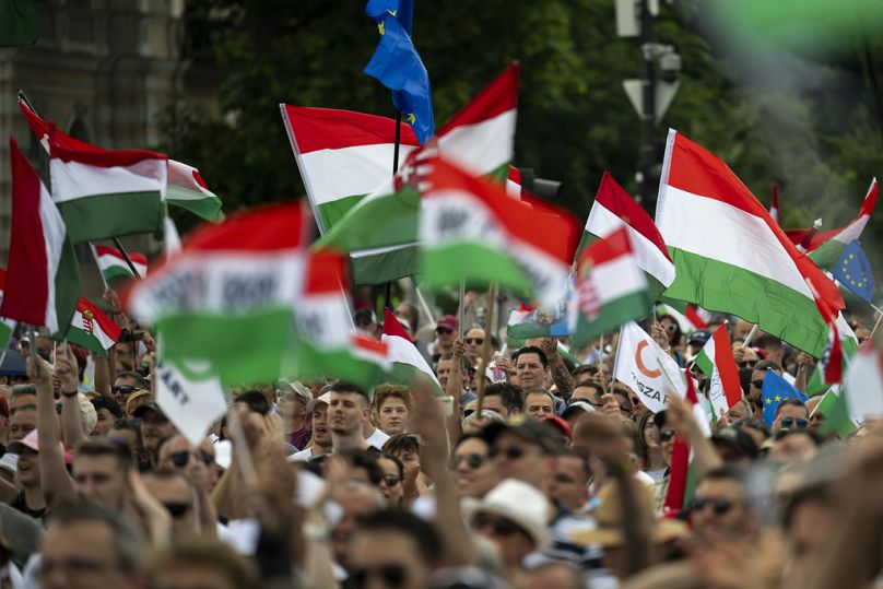 Des gens brandissent des drapeaux nationaux hongrois lors d'une manifestation, où Péter Magyar, challenger du Premier ministre hongrois Viktor Orbán, s'adresse à ses partisans, le 8 juin 2024.