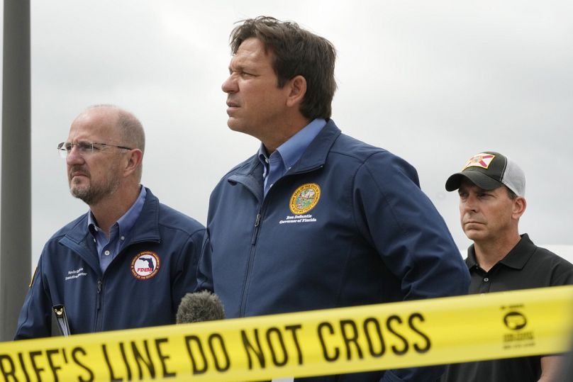 Ron DeSantis, au centre, répond aux questions lors d'une conférence de presse devant le parking du shérif du comté de St. Lucie en Floride après l'attaque de Milton