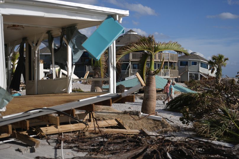 Les résidents passent devant une maison endommagée et le toit déplacé de la cabane tiki de leur communauté de maisons mobiles de plus de 55 ans après le passage de l'ouragan Milton à Englewood, en Floride, dimanche.