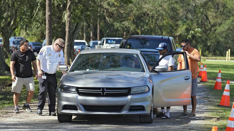 Des membres des forces de l'ordre aident un automobiliste qui est tombé en panne d'essence alors qu'il faisait la queue pour obtenir du carburant dans un dépôt samedi à Plant City, en Floride.